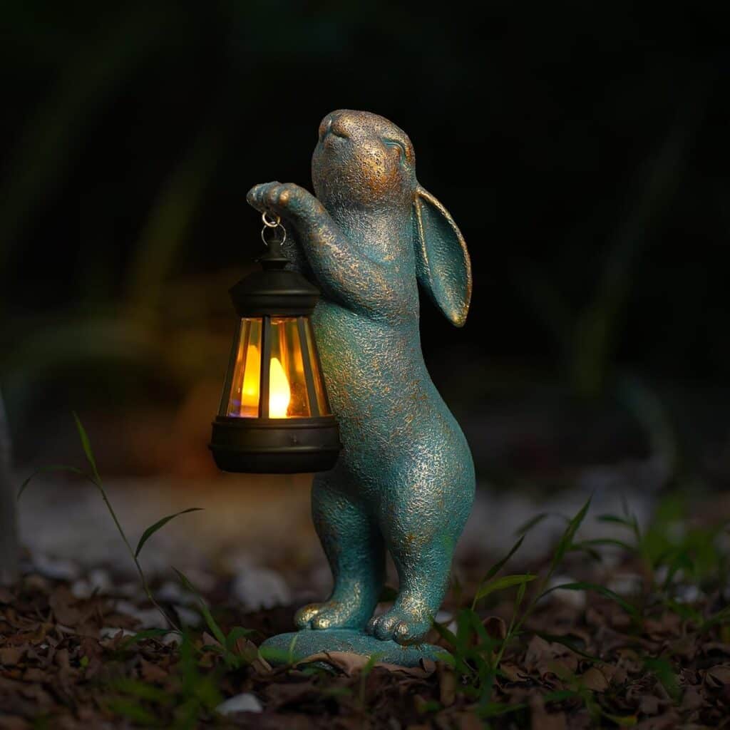 Whimsical rabbit garden statue holding a glowing lantern at night